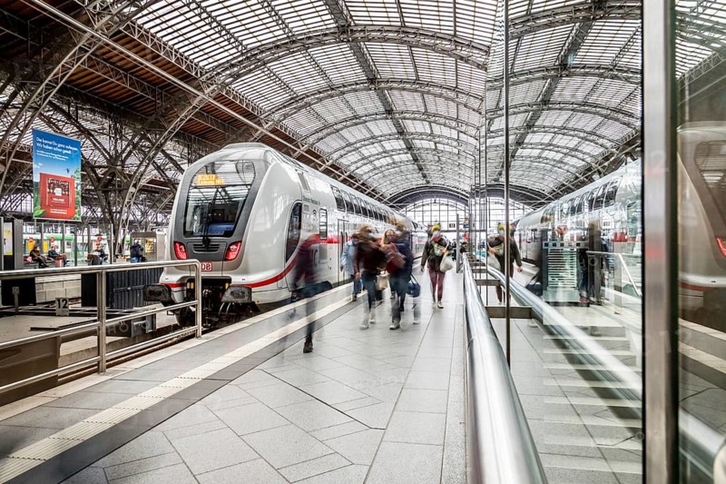Travellers waiting for trains in a station concourse with an impressive roof, Leipzig Central Station