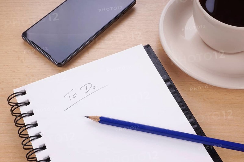 to-do list with note pad, pencil, mobile phone and cup of coffee on desk
