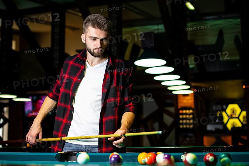 Medium shot guy with pool cue looking table
