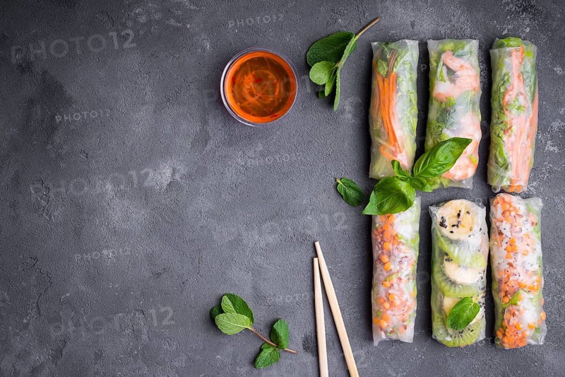 Fresh assorted spring rolls set background. Handmade asianChinese spring rolls, sauce, chopsticks. Rustic concrete background. Spring rolls with shrimps, vegetables, fruits. Space for text. Top view