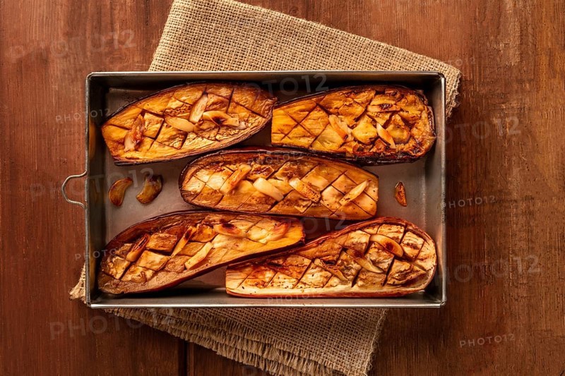 Roasted eggplants with garlic, shot from the top on a dark rustic wooden background with copy space