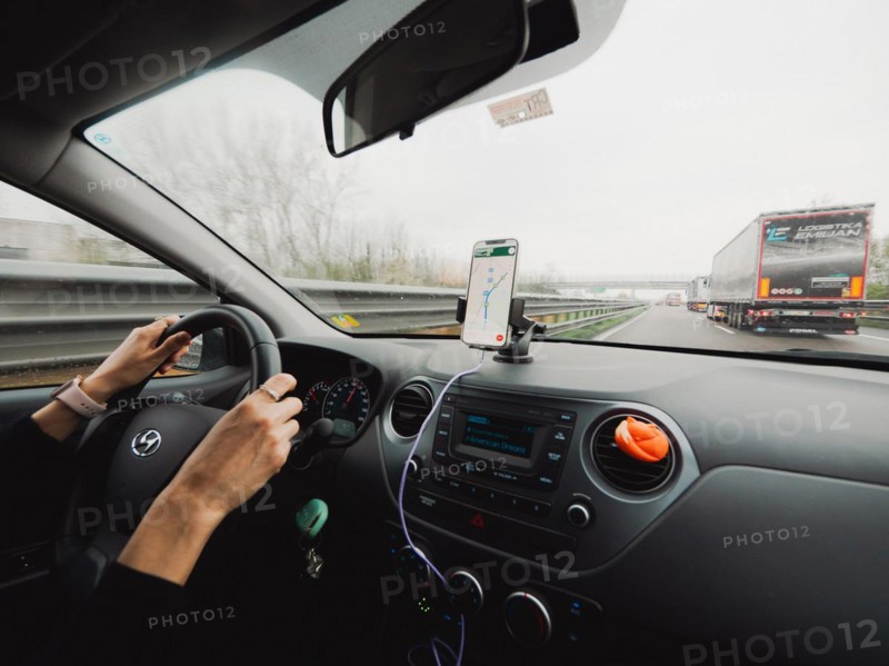 Inside view of a car with the driver's hands on the wheel and a mobile navigation system, A1 A8 highway near Milan, Italy, Europe
