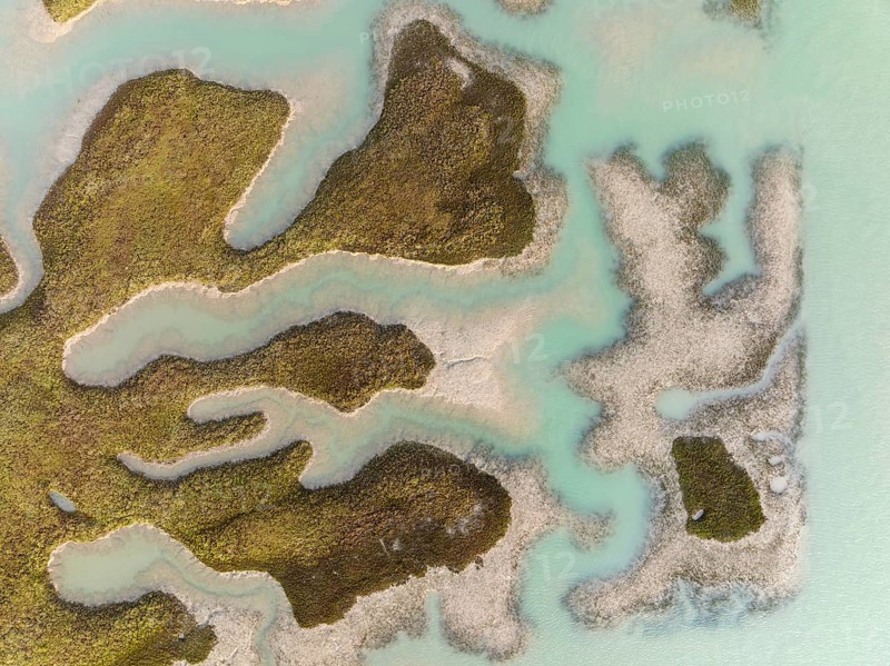 Patches of land appear while the tide is going out, in the marshland of the Bahía de Cádiz, aerial view, drone shot, Cádiz province; Andalusia; Spain