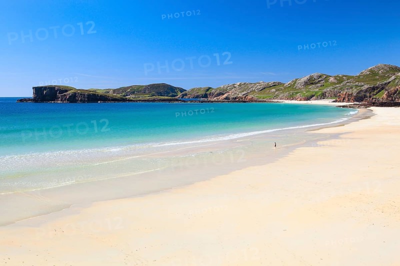 Lonely person on the idyllic sandy edge of Oldshoremore, on the west coast of Scotland