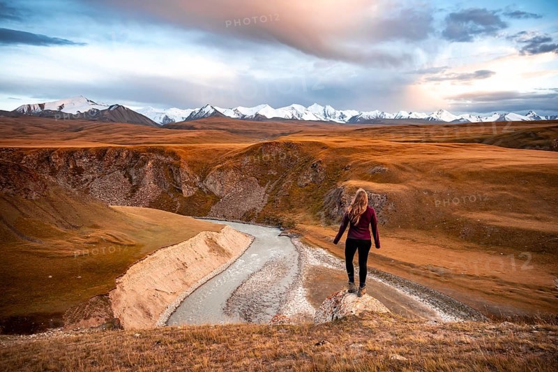 Glaciated and snow-capped mountains, Young woman in mountain landscape with yellow grass in the morning light, Tian Shan, Sky Mountains, Sary Jaz Valley, Kyrgyzstan, Asia