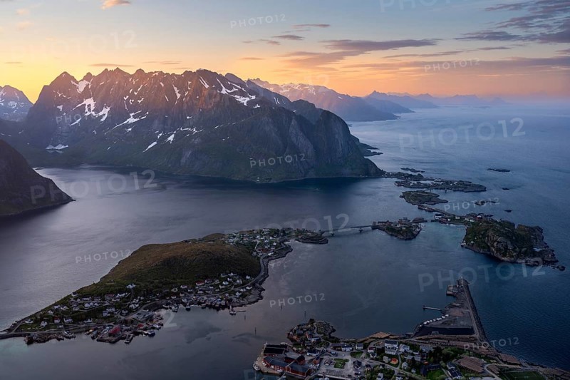 View from Reinebringen mountain to the village of Reine, Lilandstinden mountain and other mountains and the sea. At night during the midnight sun in good weather. Early summer. Reine, Moskenesoya, Lofoten, Norway, Europe