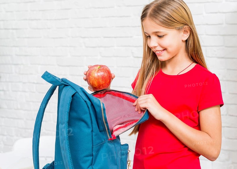 Happy girl putting apple backpack