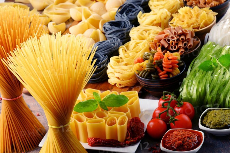 Composition with different sorts of pasta on kitchen table