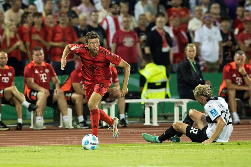 Football match, Thomas MÜLLER FC Bayern Munich left with the ball past Philipp STROMPF SSV Ulm on the ground, Donaustadion football stadium, Ulm, Germany, Europe