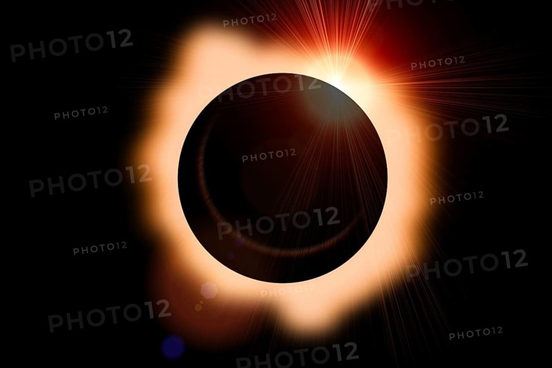 Solar eclipse with orange halo on black sky background