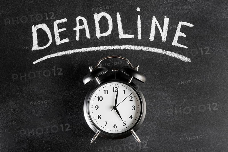 Alarm clock against chalkboard with deadline text