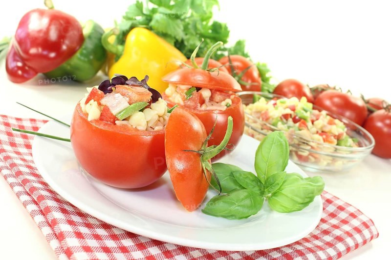 Stuffed tomatoes with pasta salad and peppers on a light-coloured background