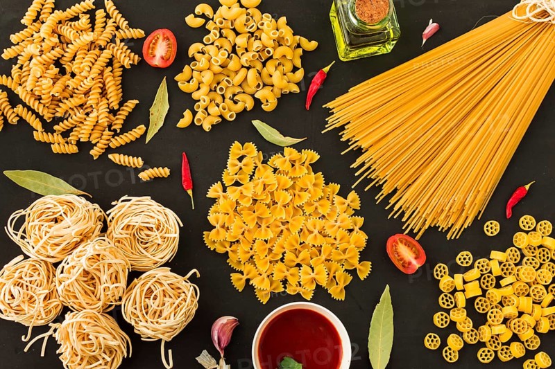Different type raw pasta with ingredients black background