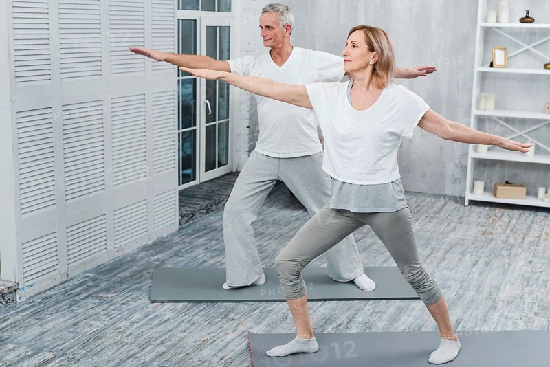 Healthy couple performing exercising yoga mat home