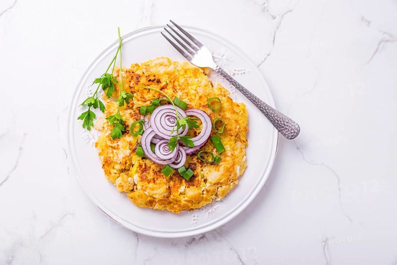 Tortilla - spanish omelet with potatoes, onions and herbs on white background