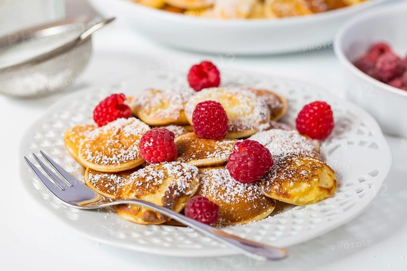 Poffertjes - small Dutch pancakes with fresh raspberries. Traditional Dutch cuisine