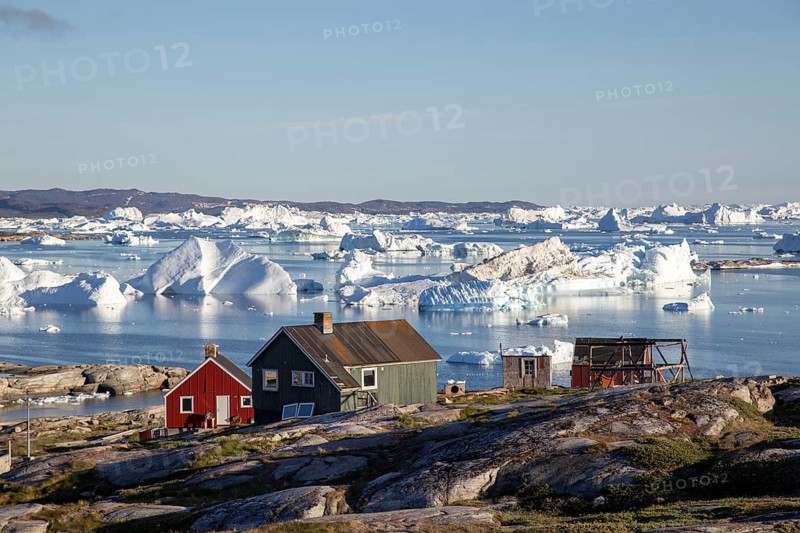 Rodebay, Greenland, July 09, 2018: Colorful wooden houses with icebergs in the background. Rodebay, also known as Oqaatsut is a fishing settlement north of Ilulissat, North America
