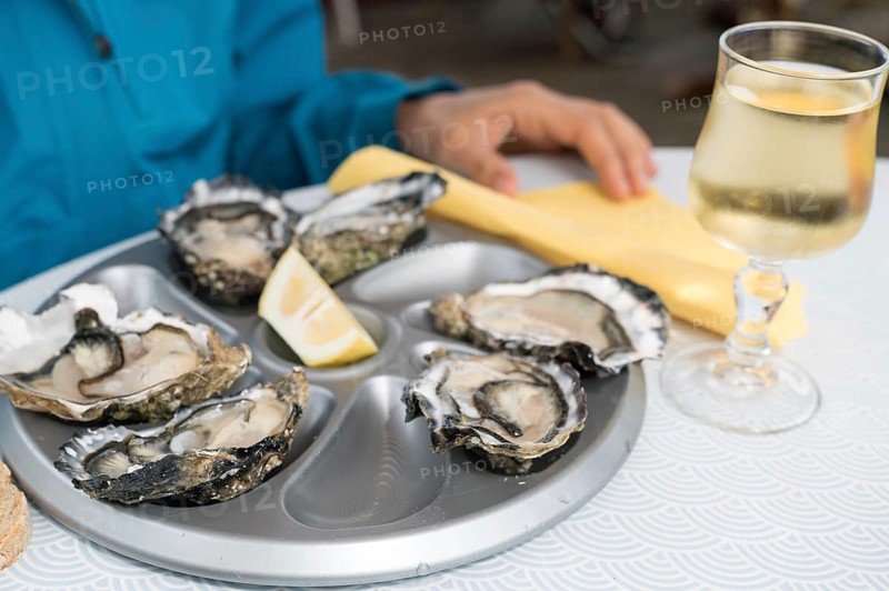 A close up of delicious fresh oysters on the half shell with a glass of French white wine