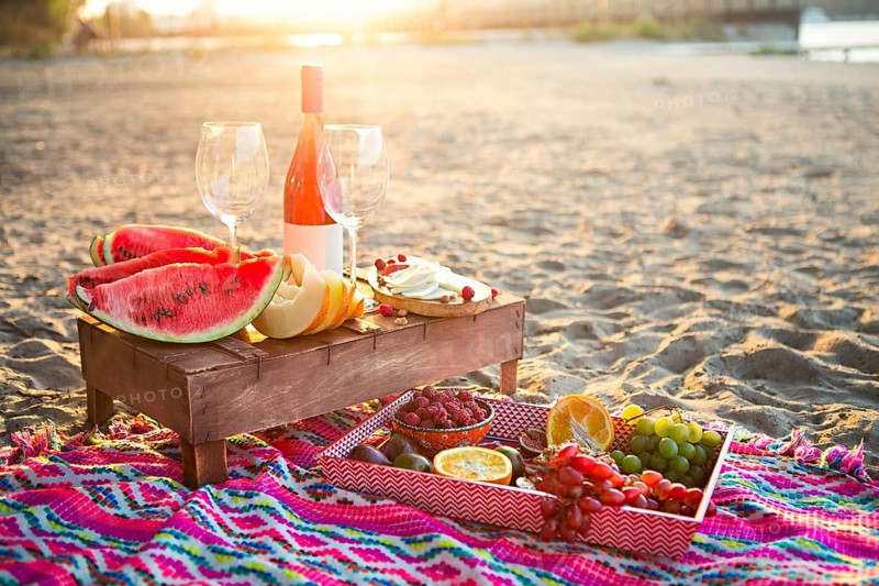 Outdoor picnic with rose wine, fruits, nuts meat and cheese