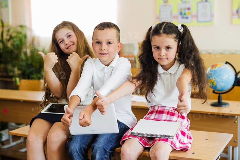 Children sitting school desk gesturing