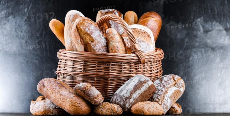 Wicker basket with assorted bakery products including loafs of bread and rolls