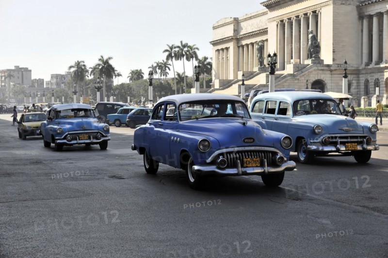 Row of vintage cars driving on a wide city street, Havana, Cuba, Central America