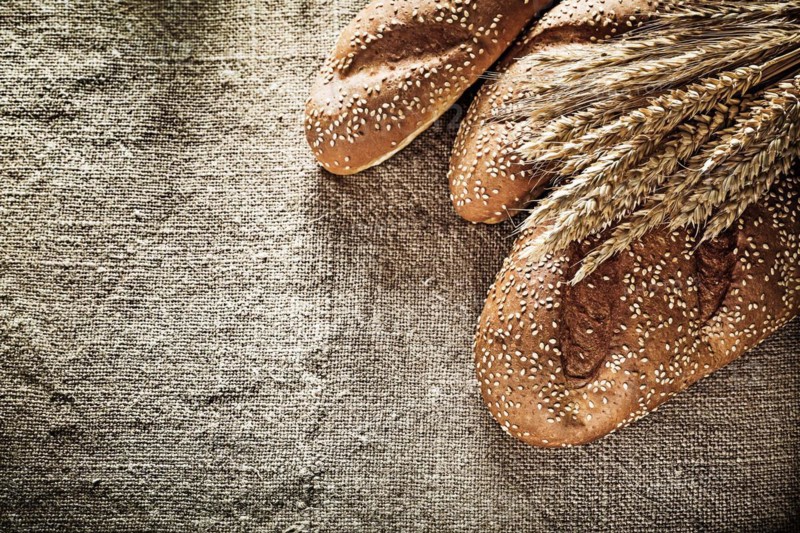 Crusty bread wheat ears on burlap background