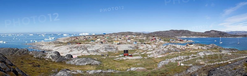 Rodebay, Greenland, July 09, 2018: Colorful wooden houses with icebergs in the background. Rodebay, also known as Oqaatsut is a fishing settlement north of Ilulissat, North America
