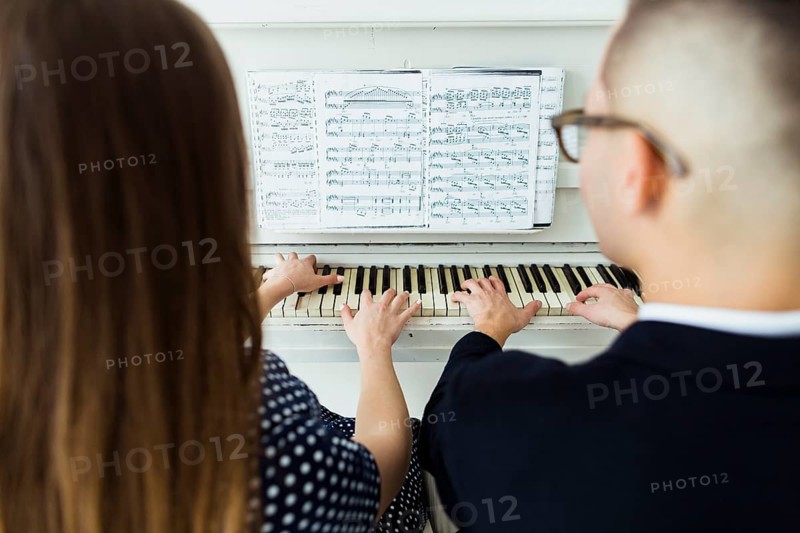 Close up couple playing piano with musical sheet