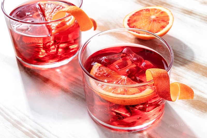 Negroni cocktail with blood oranges, on a wooden background