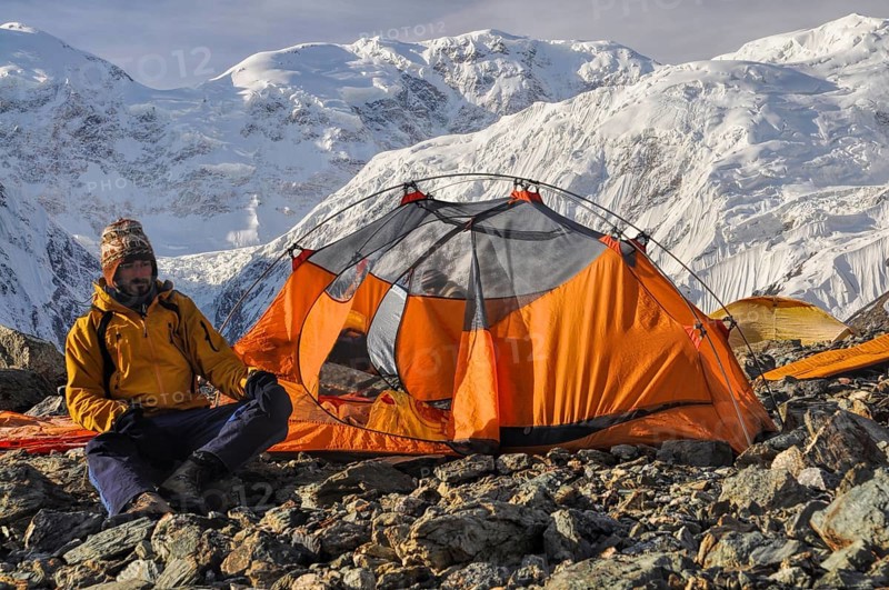 Adventurous hiker camping near Engilchek glacier in scenic Tian Shan mountain range in Kyrgyzstan