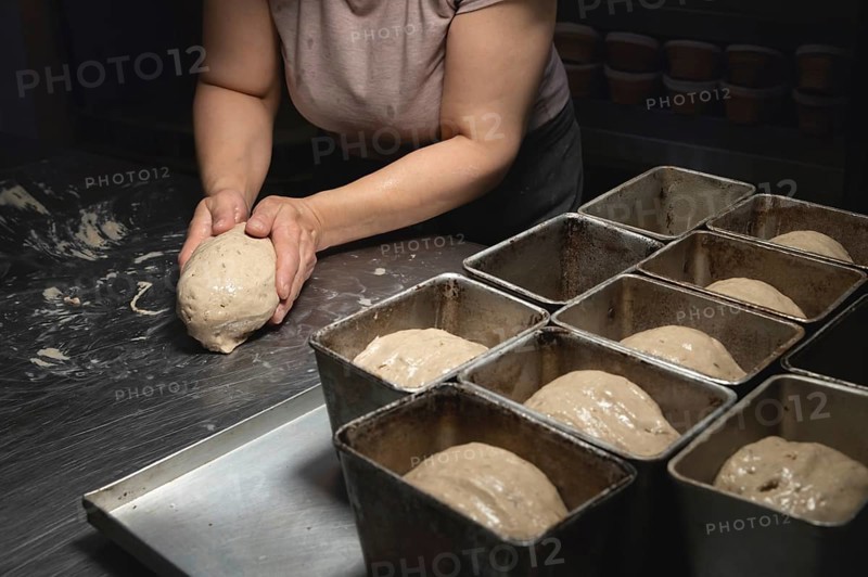 Women's hands carry out actions with raw bread. Dough before dipping into a bakery oven