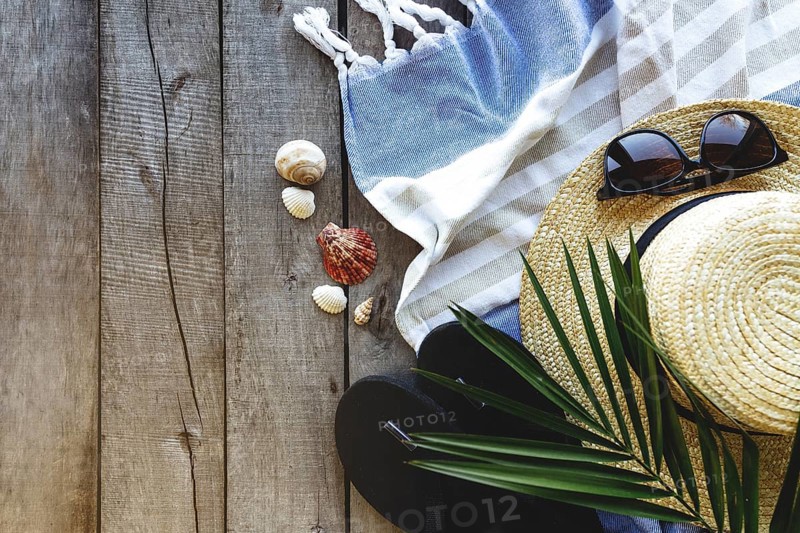 Concept of travel, vacation or weekends. Straw hat with palm leaf, shoes and eyeglasses, towel on wooden background. Relax time.