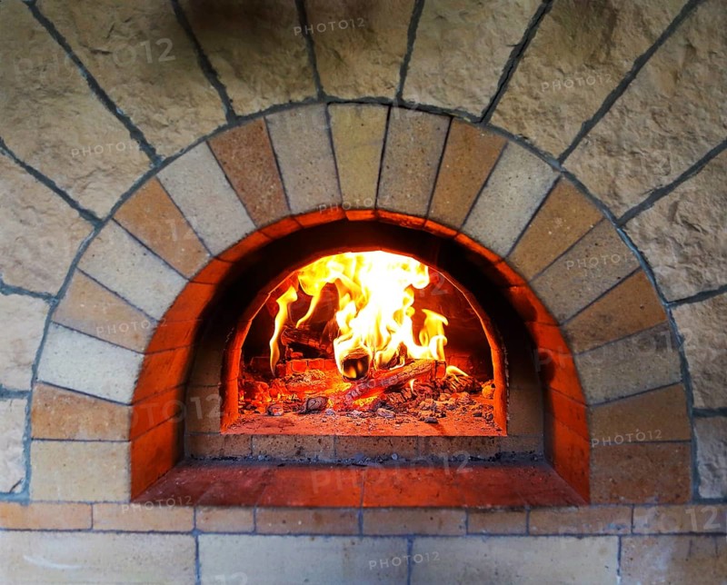 Burning firewood in traditional oven at restaurant kitchen
