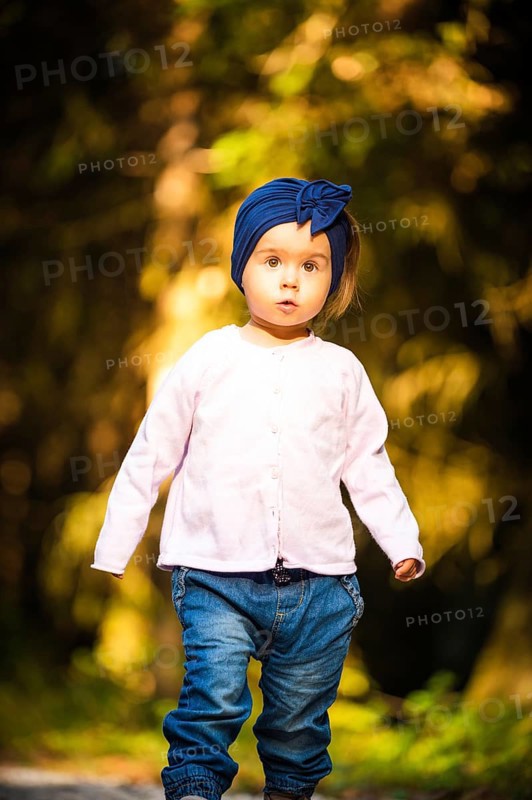 Portrait of 2 years old baby girl in forest walking by herself. Not wanting to follow parents. Concept of child independence
