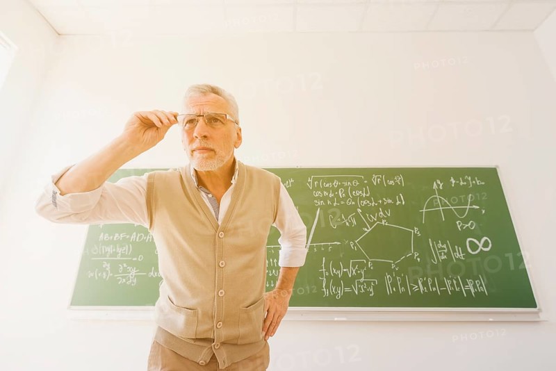 Aged professor looking through glasses classroom