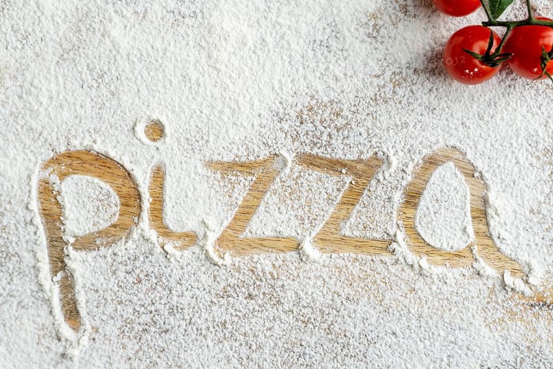 Top view pizza word written flour