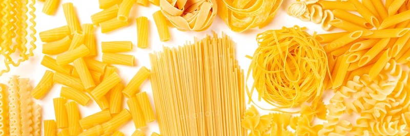 Italian pasta texture panoramic flatlay banner, overhead shot on a white background. Fusilli, farfalle, spaghetti, penne, rigatoni and other sorts