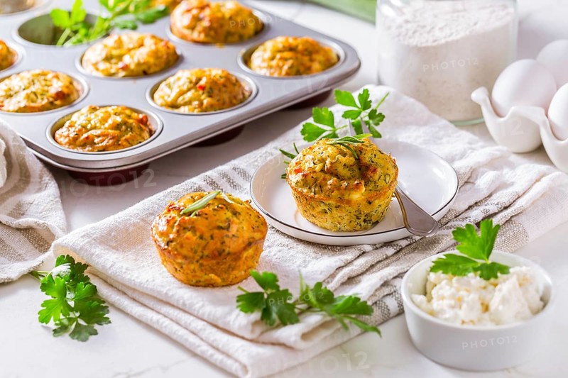 Delicious homemade zucchini muffins with feta cheese on white kitchen table