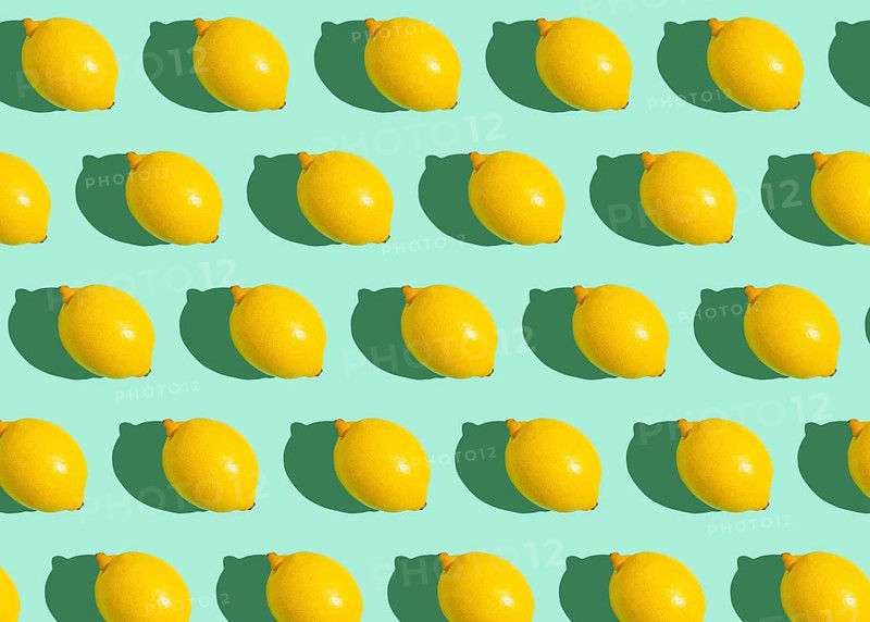 Fresh yellow whole lemons on minimal blue background on bright sun light with hard shadows pattern summer background flat lay from above, citrus food composition, space for text