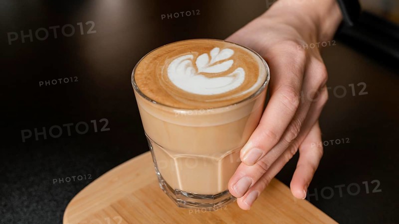 Female barista holding decorated coffee glass