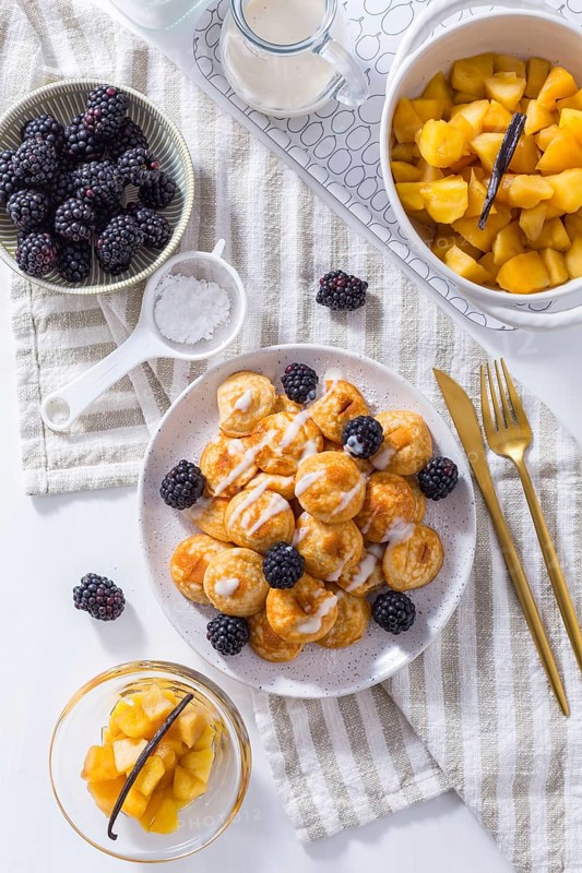 Dutch mini pancakes called poffertjes with blackberries and apple compot