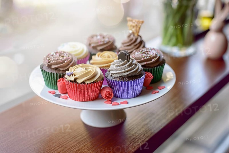 Eight deliciously sweet cupcakes covered with creamed chocolate, vanilla and various other garnishments alongside little pink heart candies