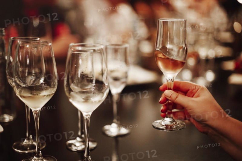 Glasses with different types of wine and human hands holding wine glasses in the background. Degustation wine