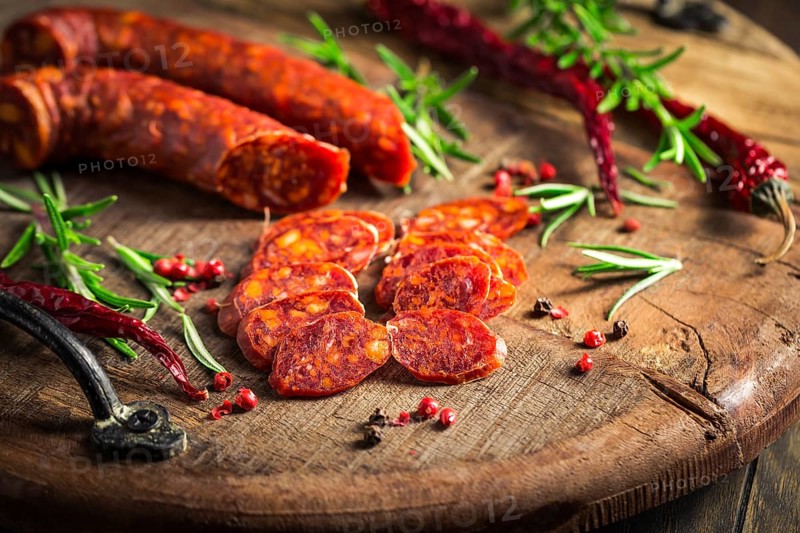 Red Spanish chorizo sausage with herbs and spices on wooden cutting board