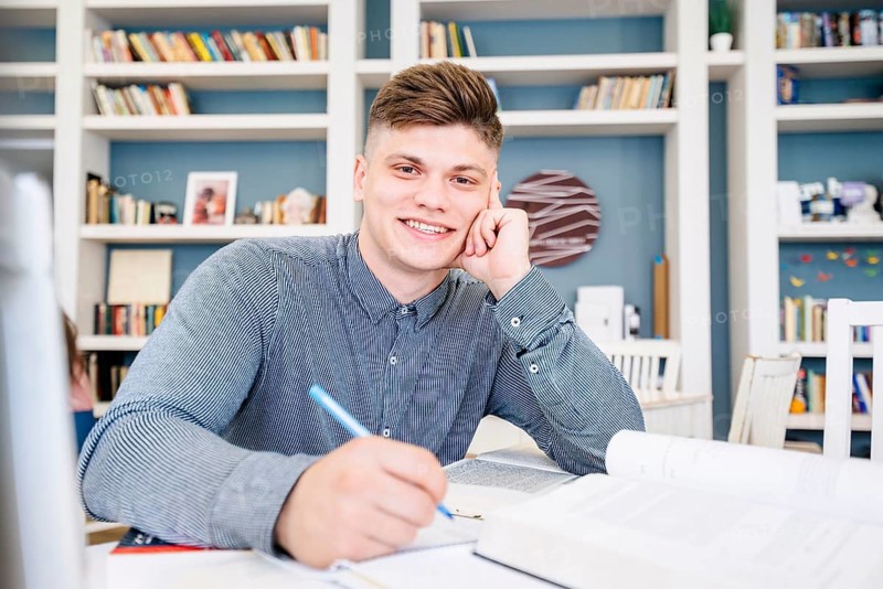 Student sitting with books pen library