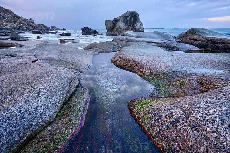 Rocks on beach of fjord of Norwegian sea in winteron sunset. Utakliev beach, Lofoten islands, Norway, Europe