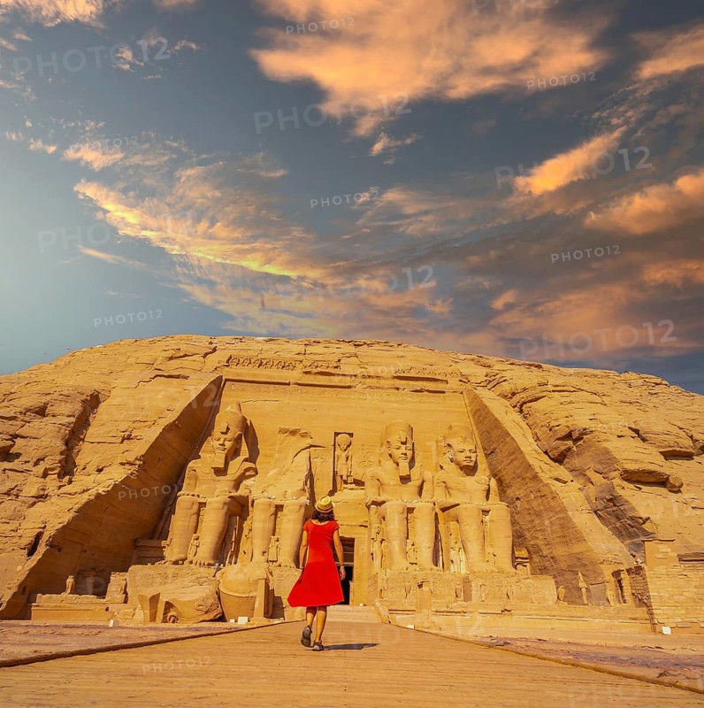 A European tourist in red dress walking towards the Abu Simbel Temple in southern Egypt in Nubia next to Lake Nasser. Temple of Pharaoh Ramses II, travel lifestyle