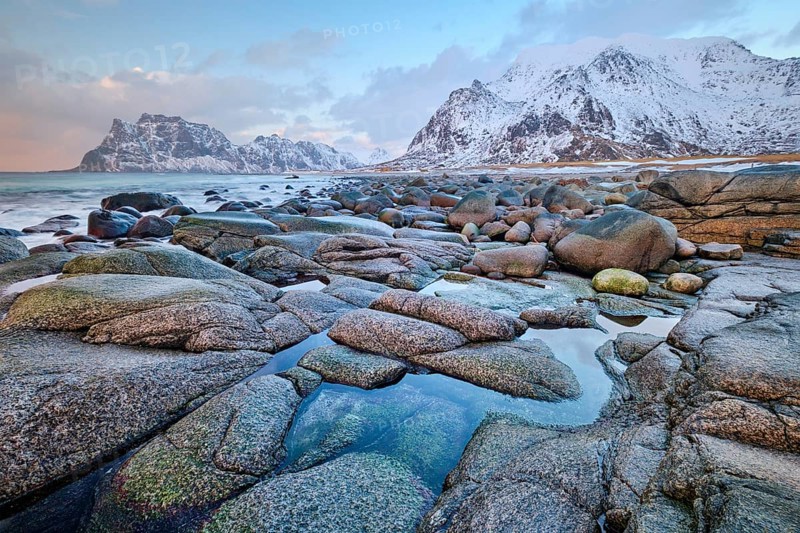 Rocks on beach of fjord of Norwegian sea in winteron sunset. Utakliev beach, Lofoten islands, Norway, Europe