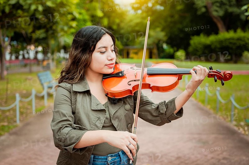 Woman playing the violin in the street. Close up of violinist girl playing in a park. Artist woman playing the violin outdoors, woman playing the violin in a nice park. Violinist woman concept